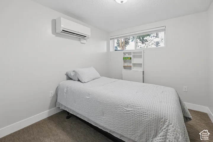 Recessed lighting, wall-mounted air conditioning unit, white trim, carpeted flooring, and a large window