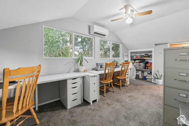 Sloped ceiling room featuring multiple windows, built-in open shelving, light gray wall paint, and a ceiling fan