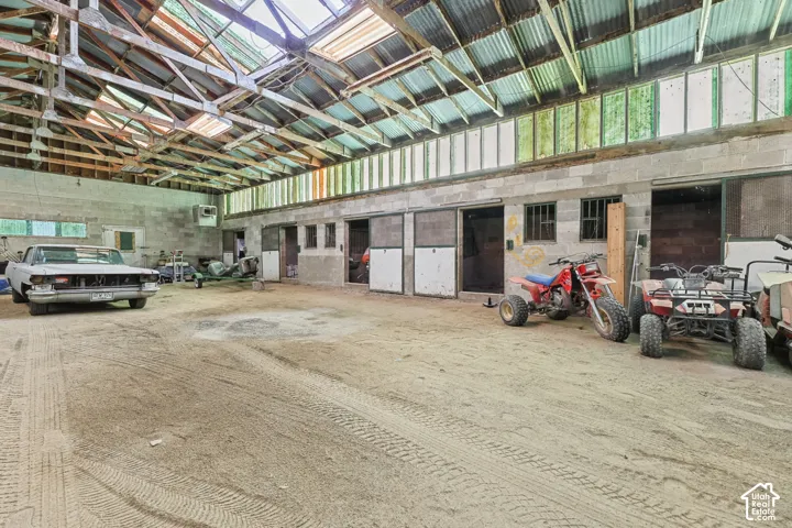 Spacious interior featuring a corrugated metal roof, exposed wooden beams, multiple sliding doors, concrete block walls, and high-level windows