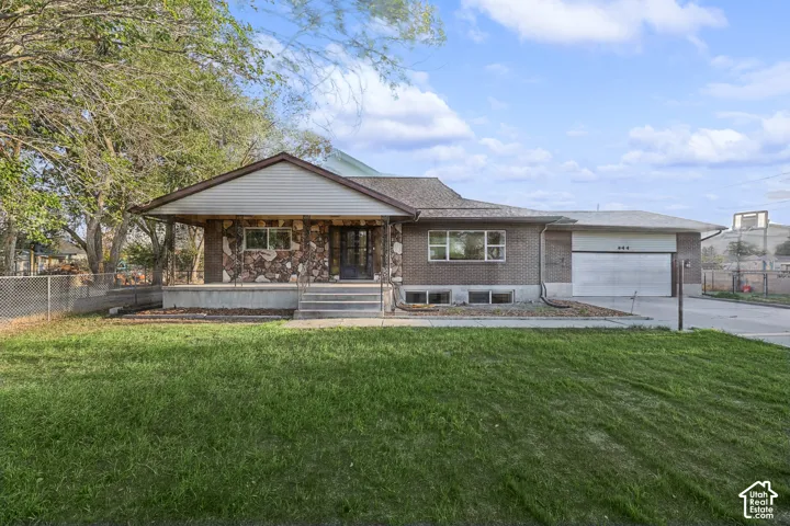 Brick exterior with stone accents, covered front porch, attached garage, and mature trees