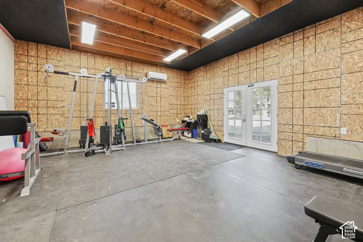 Exposed wood beam ceiling, wood-finish wall panels, large window, double glass-paned doors, and recessed lighting