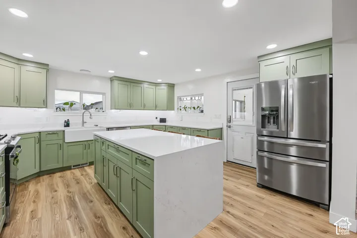 Kitchen featuring a central island with countertop, shaker-style cabinetry, wood-finish flooring, recessed lighting, and a stainless steel refrigerator
