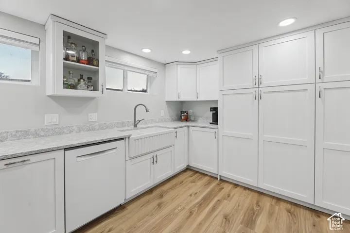 White shaker cabinetry, light-toned countertops, integrated farmhouse sink, wood-finish flooring, and recessed lighting