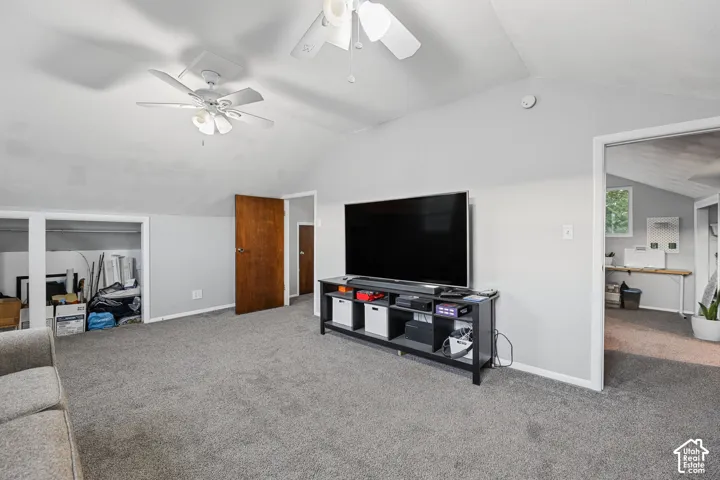 Vaulted ceiling with dual ceiling fans, light gray wall paint, and gray carpeting