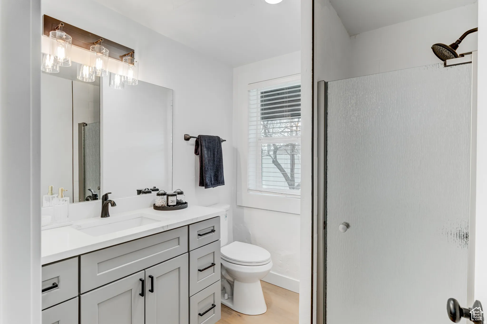 White vanity featuring a single sink, light gray cabinetry, and matte black fixtures