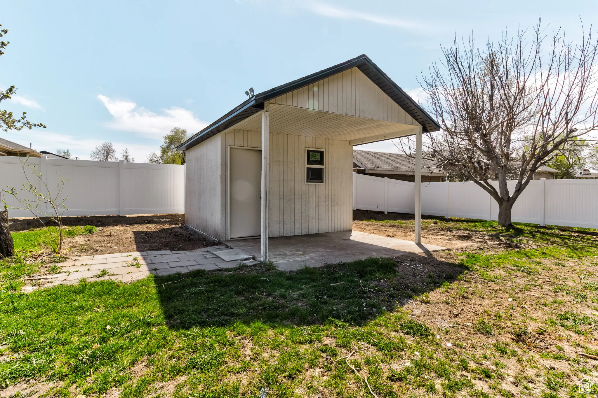 Detached outbuilding with a covered patio area, featuring a secure door and a window