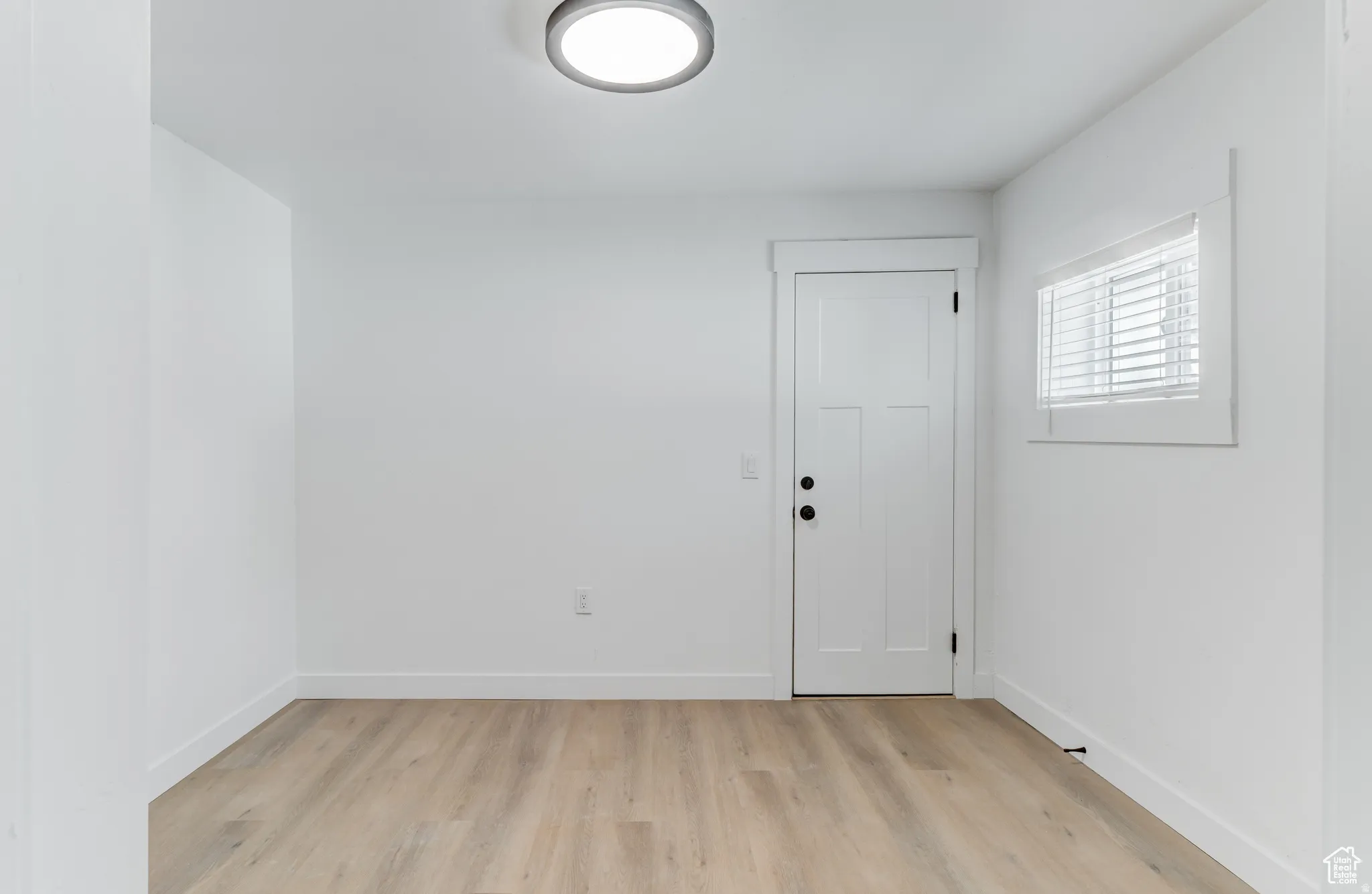 Light wood-finish flooring, white walls, and a contemporary ceiling light fixture
