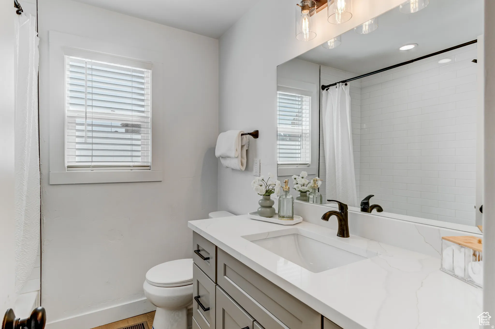Single vanity with a white countertop and integrated sink, a dark bronze-finish faucet, and a large mirror
