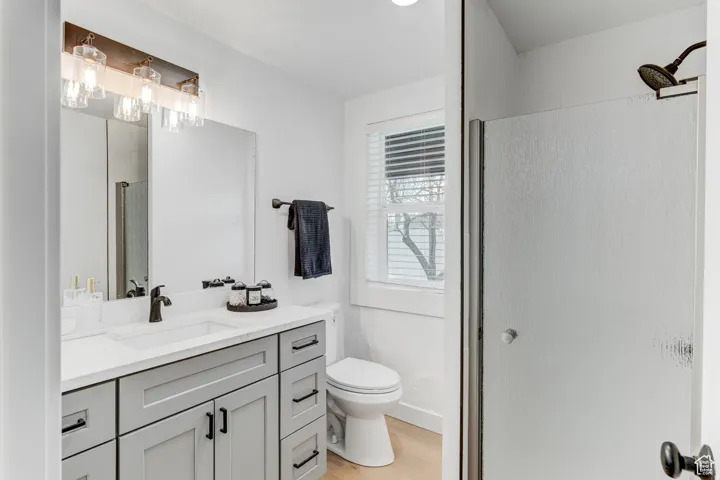 White vanity featuring a single sink, light gray cabinetry, and matte black fixtures