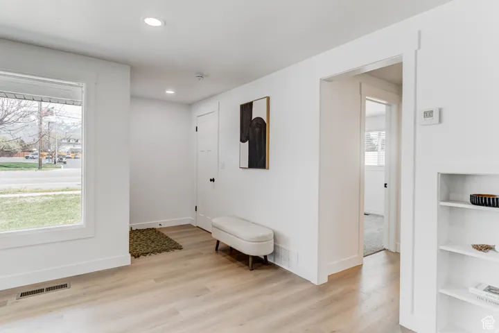 Spacious interior with neutral walls, wood-finish flooring, recessed lighting, and a built-in shelving unit