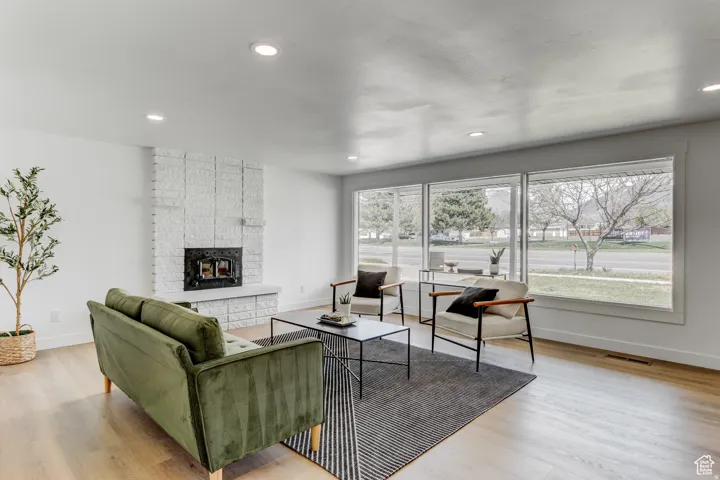 Recessed lighting, wood-finish flooring, white brick fireplace, expansive windows, white painted walls