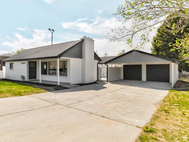 White stucco exterior with dark gray trim, covered front porch, and a two-car attached garage