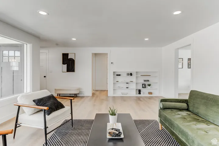 Recessed lighting illuminates wood-finish flooring, white walls, and built-in shelving
