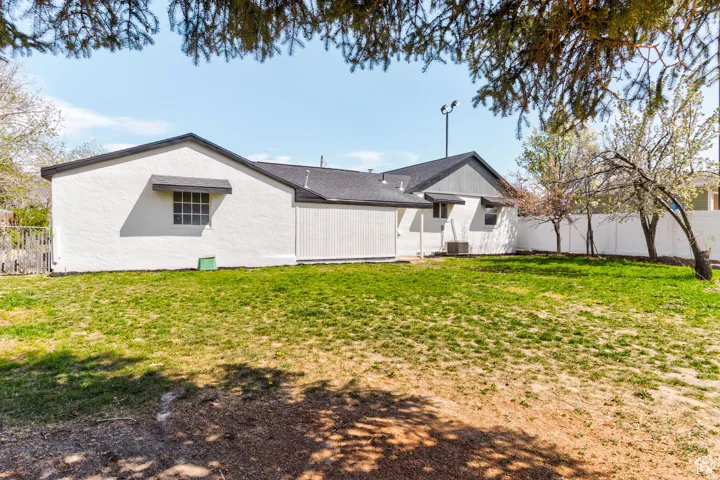 Expansive yard with green lawn, white privacy fencing, and mature trees