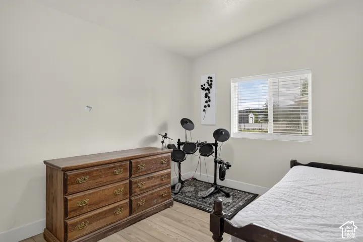 Light wood-finish flooring with white baseboards and a prominent window