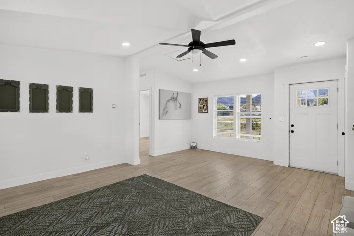 Bright living area featuring wood-finish flooring, recessed lighting, a ceiling fan, and a transom window above the entry door