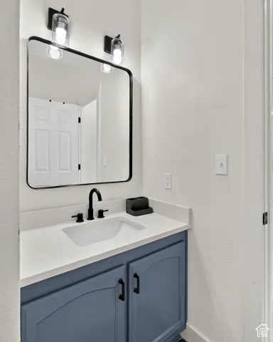 Vanity with a white countertop and integrated sink, matte black faucet, and blue cabinetry