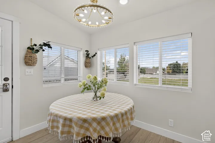 Multiple windows with white blinds, wood-finish flooring, and a decorative overhead light fixture
