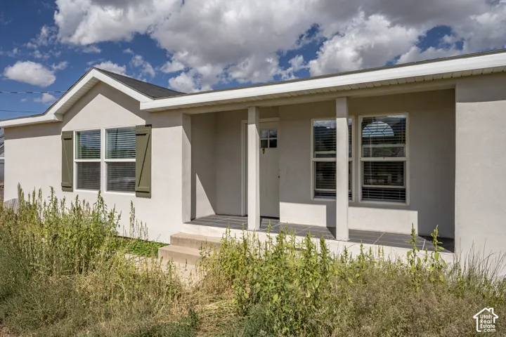 Stucco exterior with a covered porch entry, multiple windows, and decorative window shutters