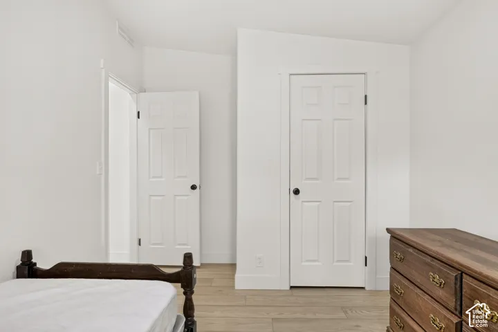 Light wood-finish flooring, white painted walls, and white six-panel doors