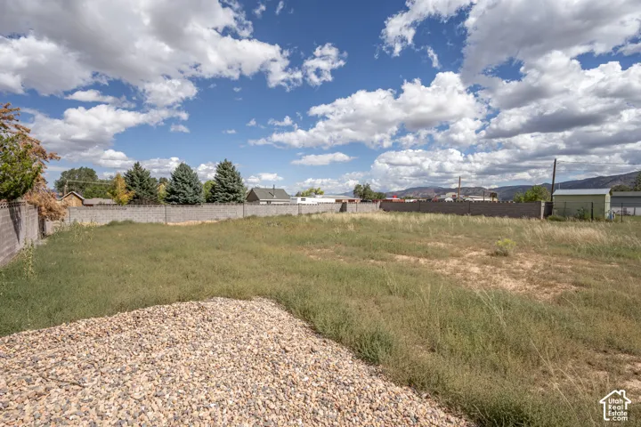 Expansive lot featuring a gravel pad, natural landscaping, and a concrete perimeter wall
