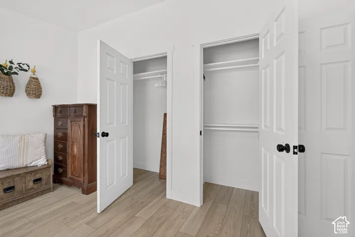 Light wood-finish flooring, white paneled doors with matte black hardware, and double closets featuring built-in shelving