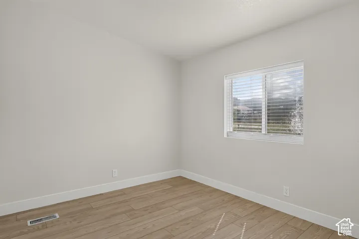 Light-toned walls, wood-finish flooring, and a window with horizontal blinds