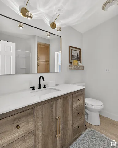 Wood-finish vanity with white countertop, undermount sink, and matte black faucet