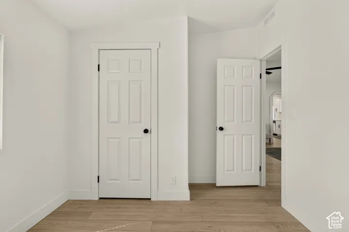 Wood-finish flooring, white paneled doors, and bright white walls
