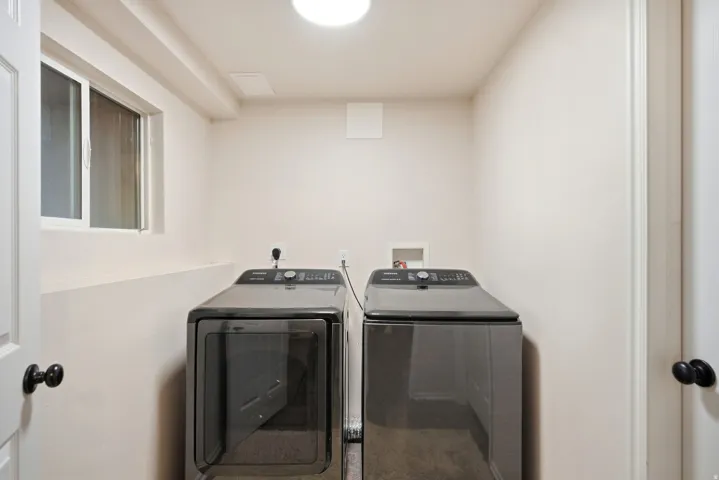 Dedicated laundry space with light-toned walls and a window for natural illumination