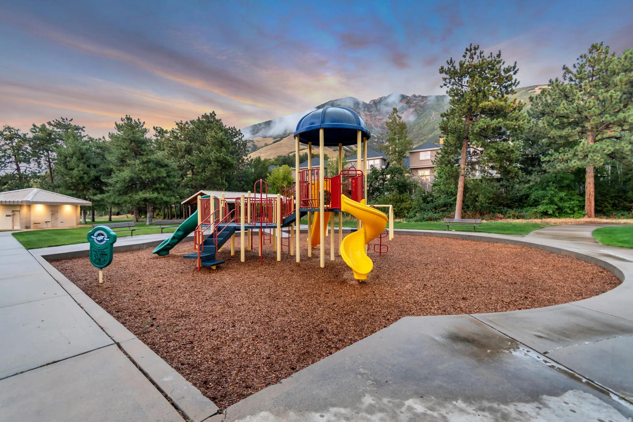 Recreational playground area featuring a multi-level play structure with slides and climbing elements, surrounded by woodchip surfacing