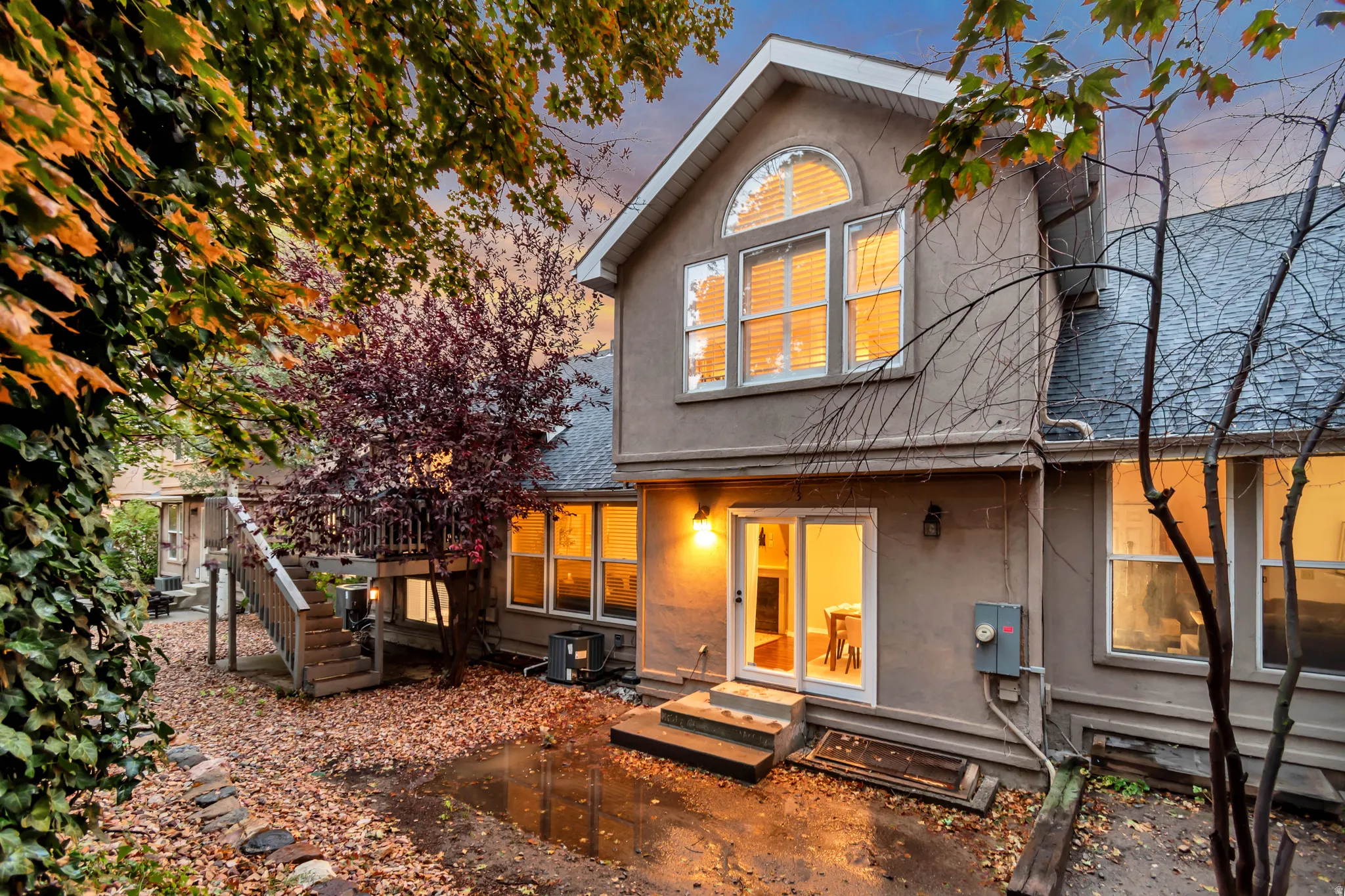 Stucco exterior with a multi-level deck, ground-level patio, and mature trees
