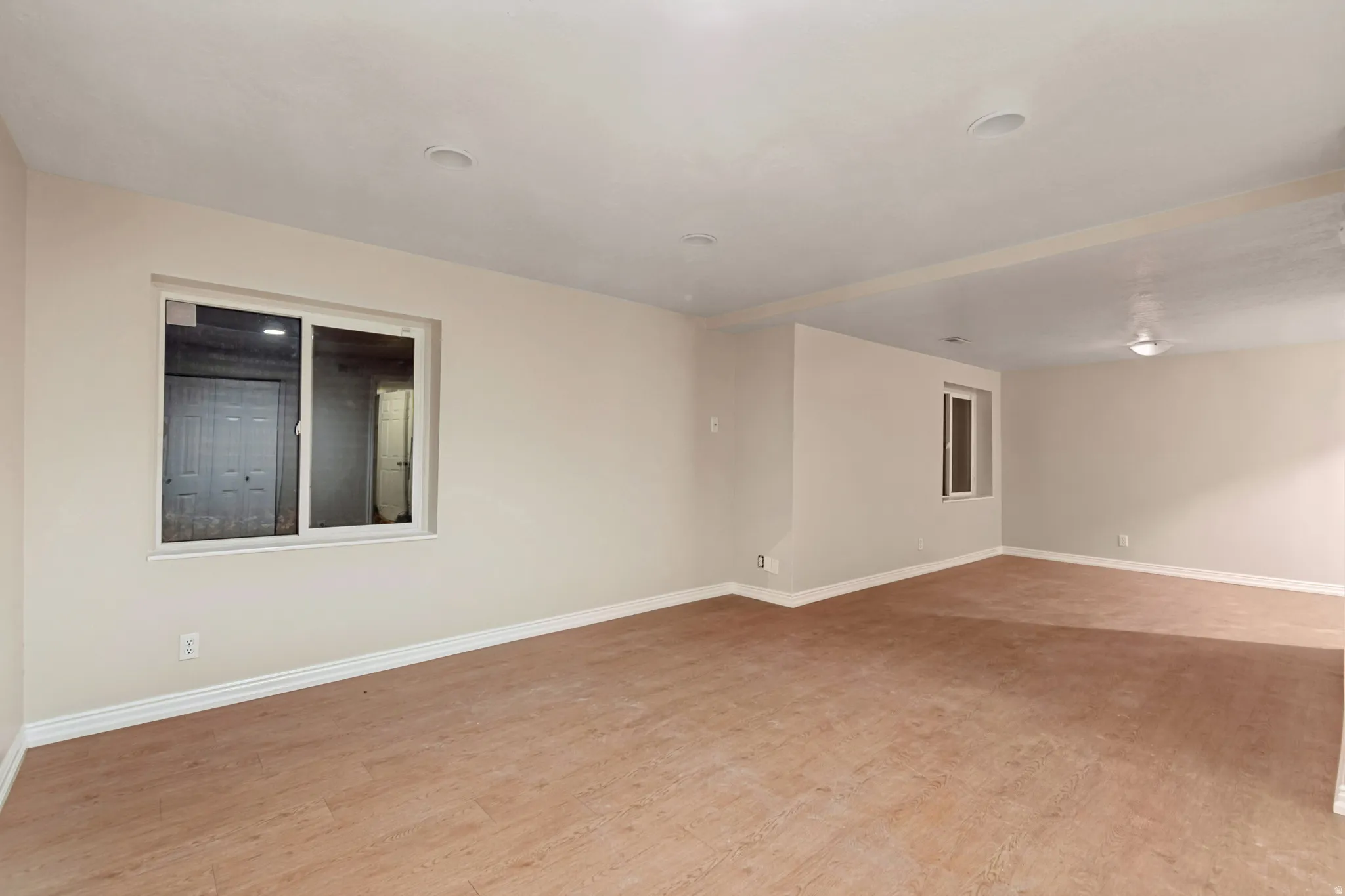 Spacious room with wood-finish flooring, recessed lighting, and multiple windows