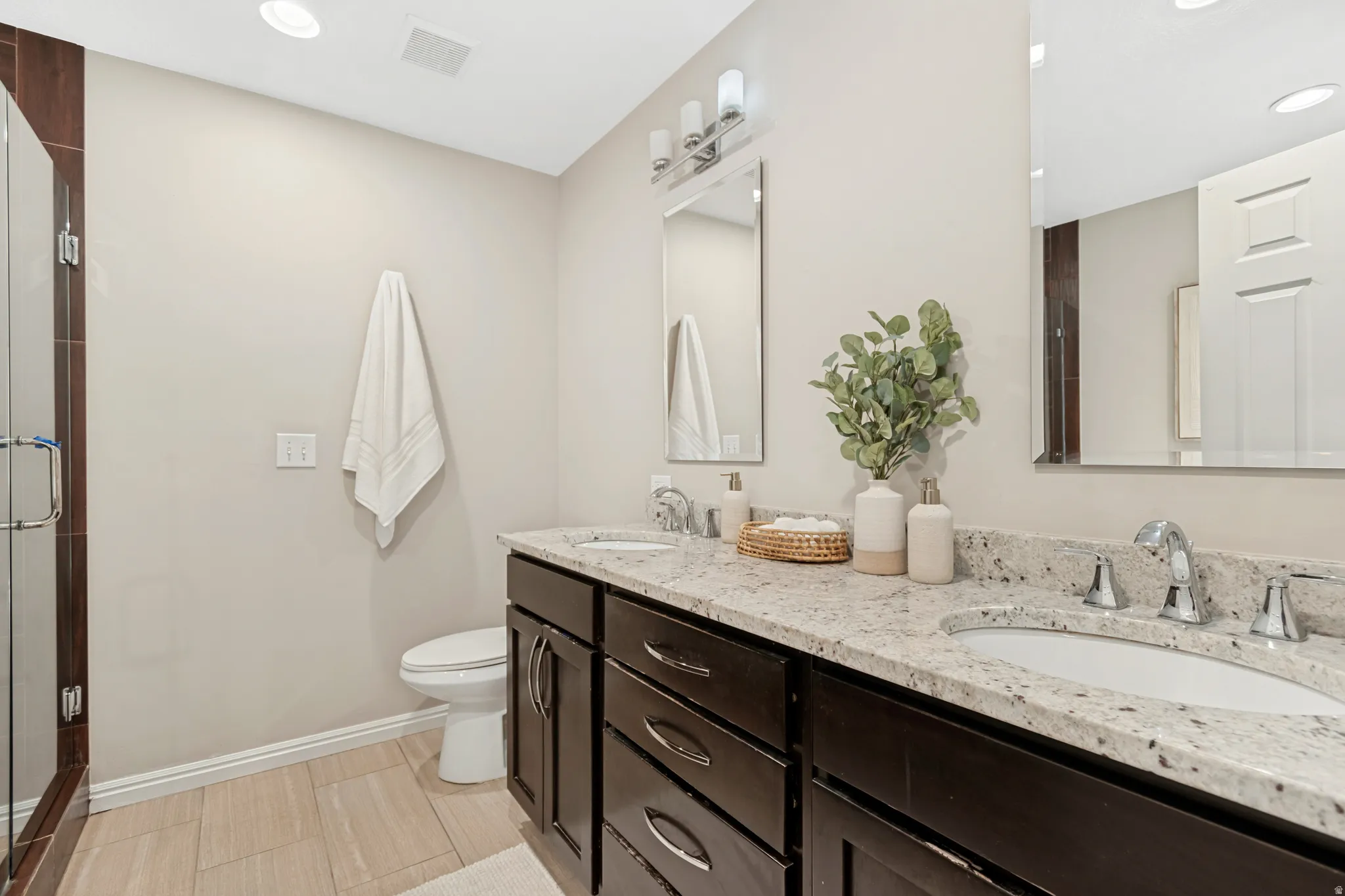 Dual vanity with dark wood cabinetry and light-toned stone countertops