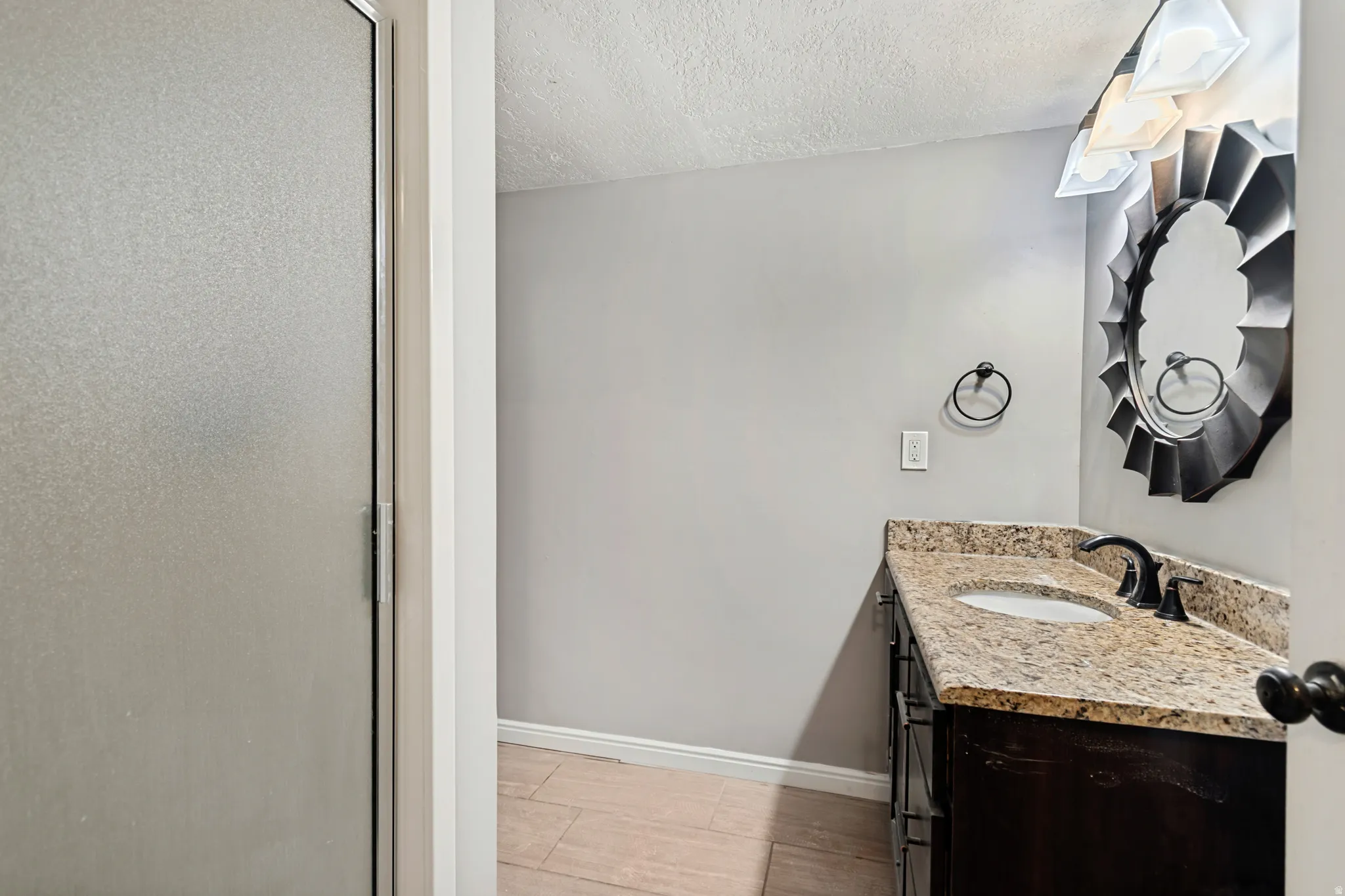 Bathroom featuring a vanity with an integrated sink, stone countertop, dark wood-finish cabinetry, and tiled flooring