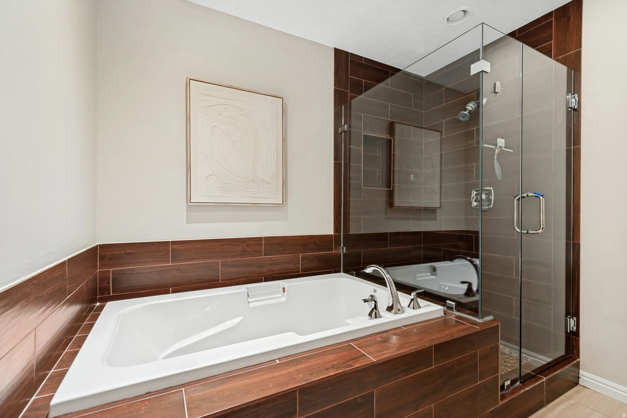 White soaking tub with deck-mounted chrome fixtures, set within wood-finish tiled surround