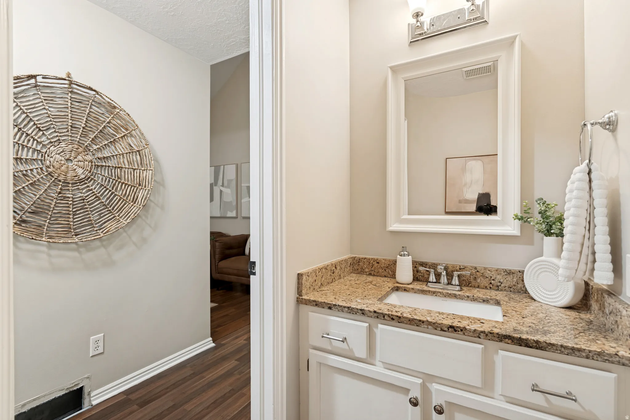 Vanity with a granite-style countertop, undermount sink, and chrome faucet