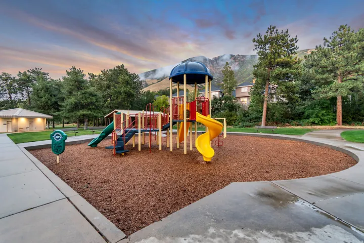 Recreational playground area featuring a multi-level play structure with slides and climbing elements, surrounded by woodchip surfacing