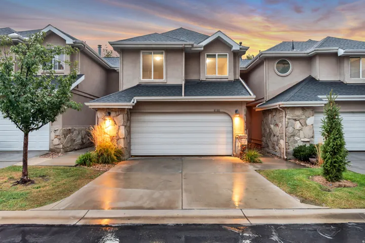 Stucco exterior with stone accents, attached two-car garage, and established landscaping