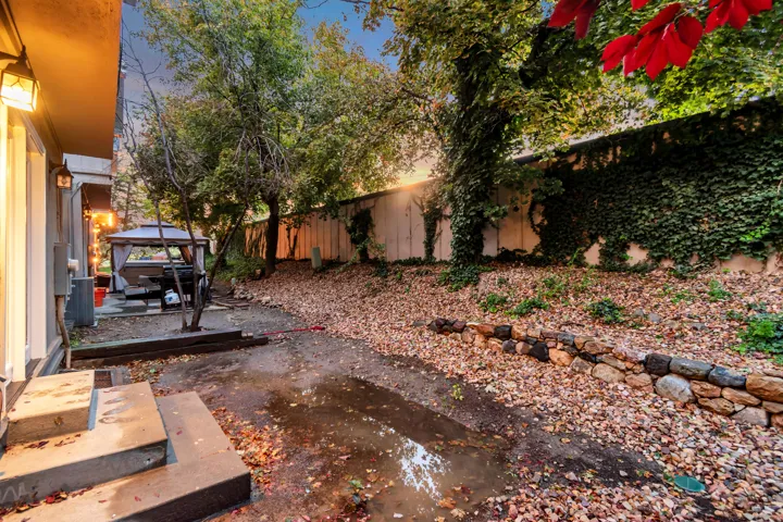 Tiered backyard featuring a stone retaining wall, mature trees, and an ivy-covered privacy fence