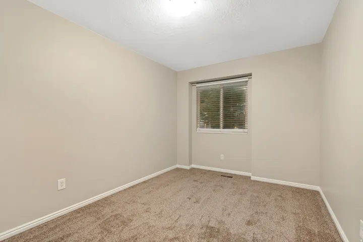 Neutral wall paint, carpet flooring, and a single window with blinds