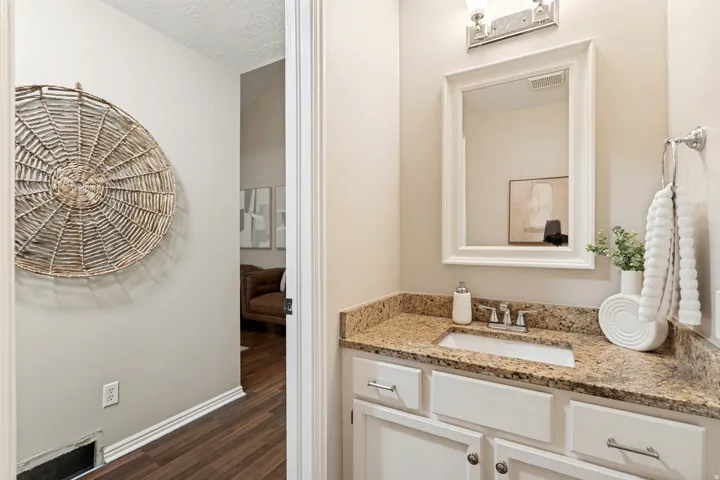 Vanity with a granite-style countertop, undermount sink, and chrome faucet