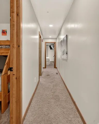 Hallway with recessed lighting, light-toned carpeting, and wood-finish door frames