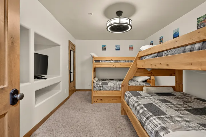 Built-in entertainment niche, solid wood door, dark bronze door hardware, wood-finish bunk beds, and a contemporary ceiling light fixture