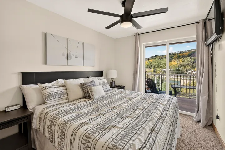 Bedroom featuring a ceiling fan, a private balcony with a dark railing, and a sliding glass door