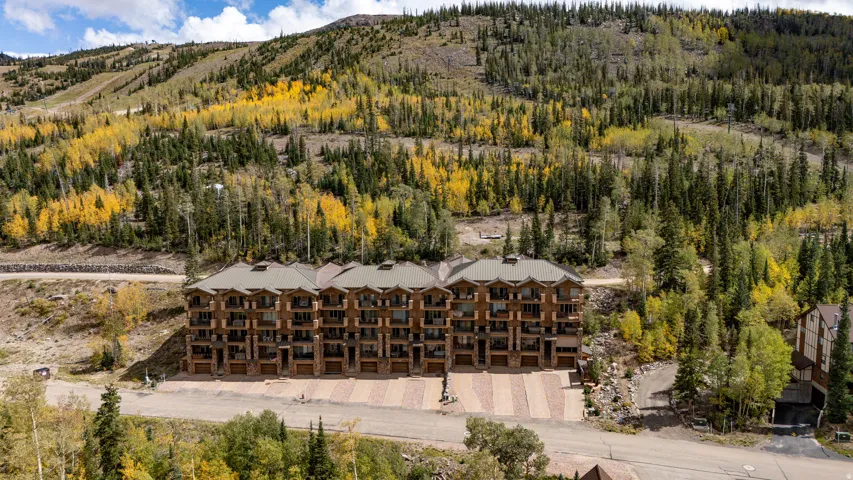 Multi-story building featuring stone and wood-finish siding, multiple balconies, and a stone-paver driveway