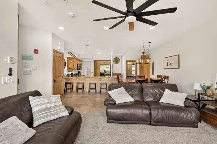 Recessed lighting, ceiling fan, wood-finish cabinetry, tile flooring, and a dining area with a chandelier