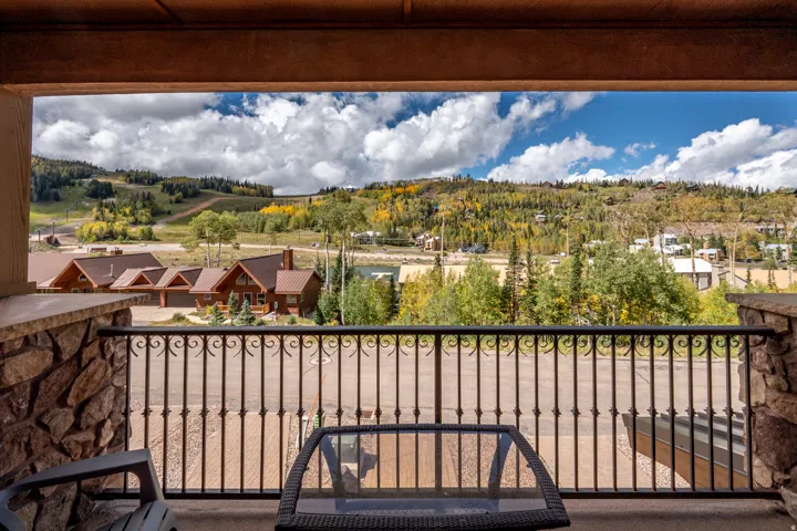 Stone veneer balcony with an ornate wrought iron railing overlooking a scenic mountainous landscape