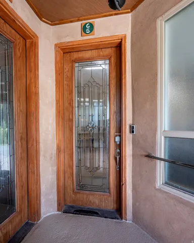 Wood-finish entry door with decorative glass inserts, textured wall finish, and wood-finish ceiling trim
