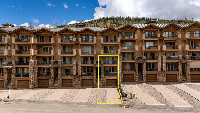 Stone and stucco exterior with multiple balconies, wood-finish garage door, and a private driveway